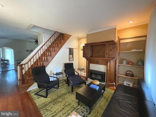 living room with hardwood / wood-style flooring, ceiling fan, ornamental molding, and a fireplace