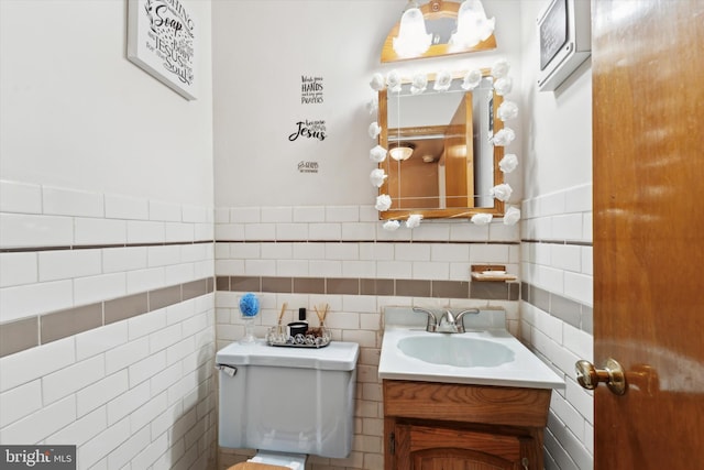 bathroom with vanity, toilet, and tile walls