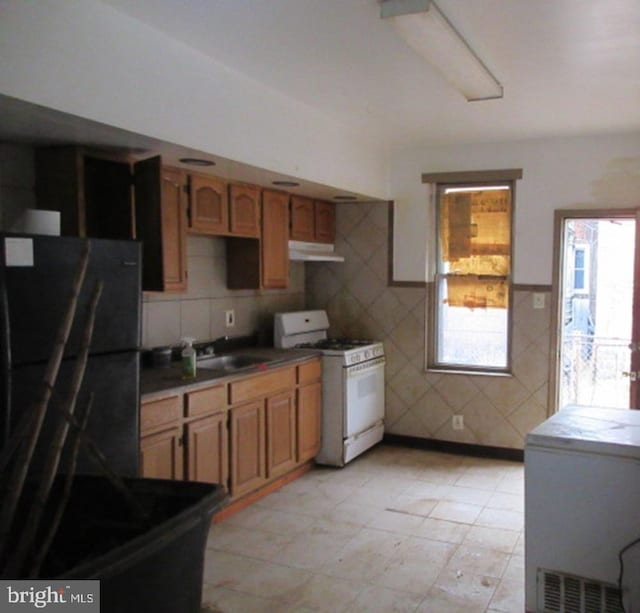 kitchen featuring white gas range, black refrigerator, refrigerator, and sink