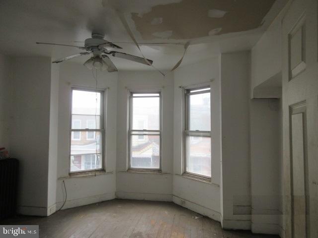 empty room with ceiling fan, light hardwood / wood-style floors, and radiator heating unit