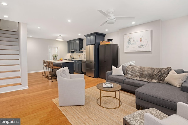 living room with sink, light wood-type flooring, and ceiling fan