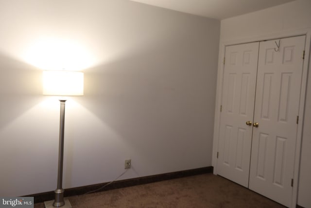 unfurnished bedroom with dark carpet and a closet