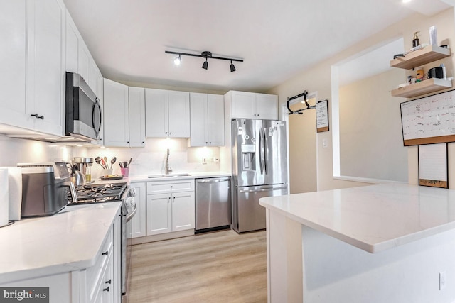 kitchen featuring white cabinetry, sink, stainless steel appliances, and light hardwood / wood-style flooring