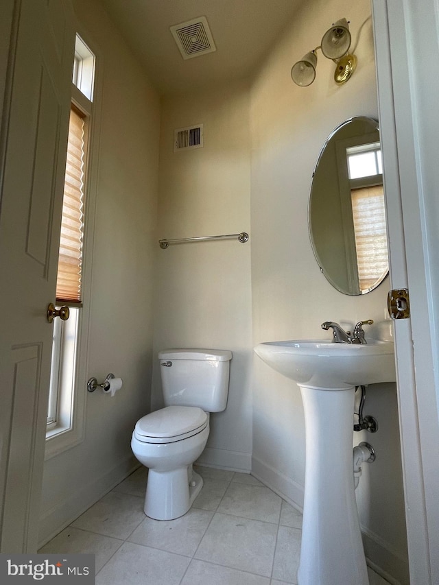 bathroom with tile patterned flooring, toilet, and a healthy amount of sunlight