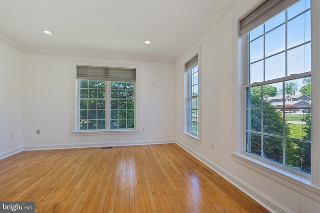 empty room with crown molding and light hardwood / wood-style floors