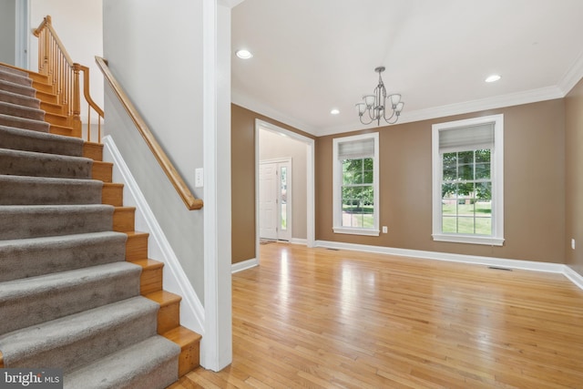 entrance foyer featuring an inviting chandelier, crown molding, and light hardwood / wood-style flooring