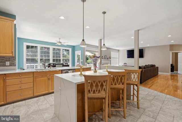 kitchen featuring sink, a breakfast bar, hanging light fixtures, a center island, and light brown cabinets