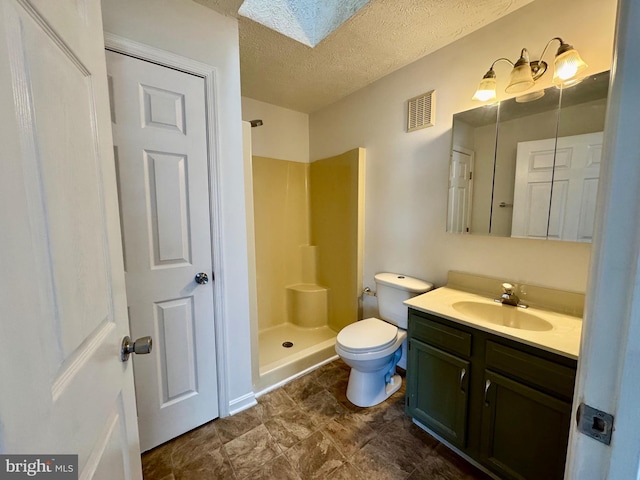 bathroom featuring a skylight, vanity, walk in shower, toilet, and a textured ceiling