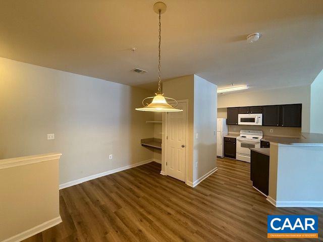 kitchen featuring decorative light fixtures, dark wood-type flooring, and white appliances