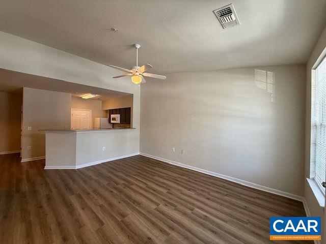 unfurnished living room with a ceiling fan, baseboards, visible vents, and dark wood-style flooring