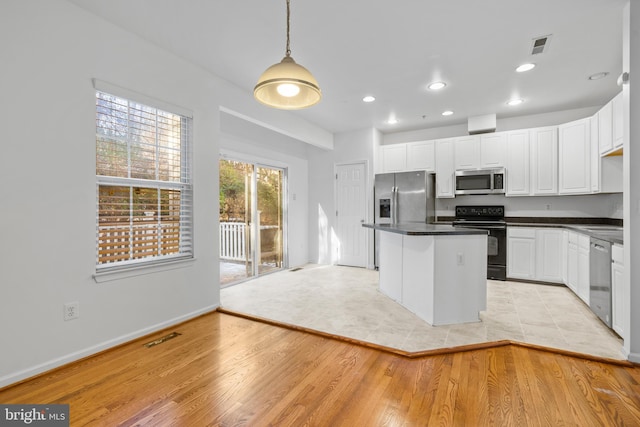 kitchen featuring decorative light fixtures, a center island, light wood-type flooring, appliances with stainless steel finishes, and white cabinets