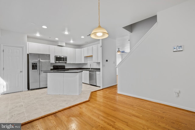 kitchen with white cabinetry, sink, hanging light fixtures, ceiling fan, and stainless steel appliances