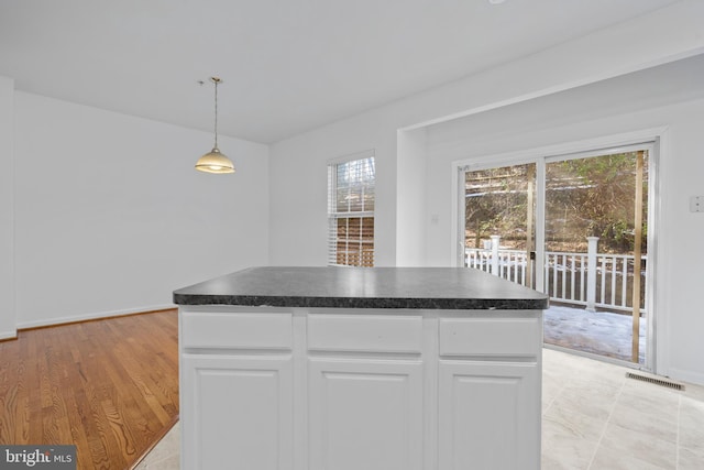 kitchen with white cabinetry, a kitchen island, light hardwood / wood-style floors, and decorative light fixtures