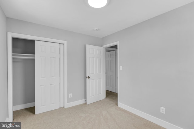 unfurnished bedroom featuring a closet and light colored carpet