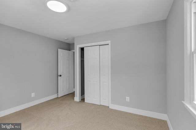 unfurnished bedroom featuring light carpet and a closet