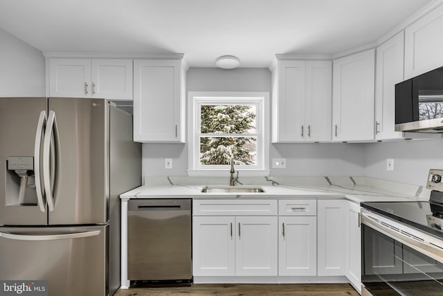 kitchen with white cabinets, stainless steel appliances, light stone countertops, and sink