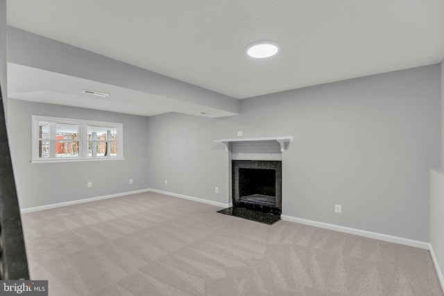 unfurnished living room with a high end fireplace and light colored carpet