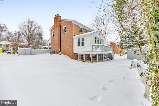 snow covered house featuring an outbuilding, a deck, and central air condition unit