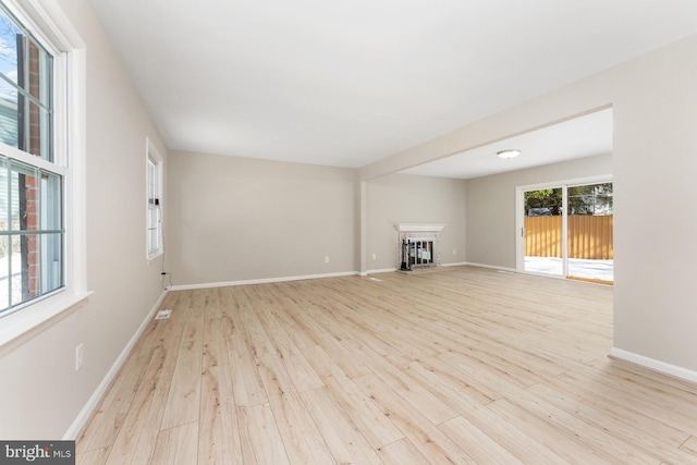 unfurnished living room with light hardwood / wood-style flooring and a brick fireplace