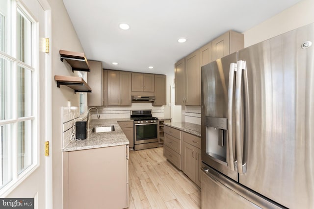 kitchen featuring sink, light hardwood / wood-style flooring, ventilation hood, decorative backsplash, and appliances with stainless steel finishes