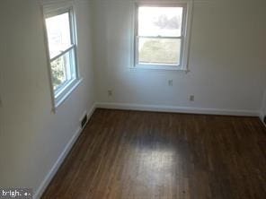 unfurnished room with dark wood-style floors and baseboards