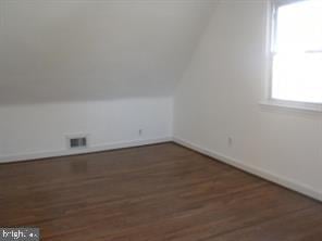 additional living space featuring dark wood finished floors, visible vents, and baseboards