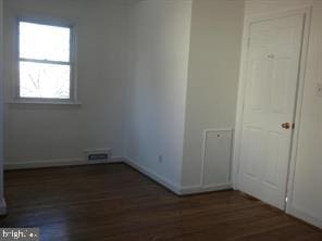 spare room with visible vents, dark wood finished floors, and baseboards