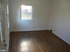 unfurnished room with baseboards and dark wood finished floors