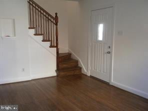 entryway with stairs, dark wood-type flooring, and baseboards