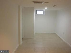 basement with light tile patterned floors, visible vents, and baseboards