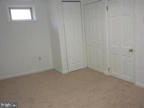 unfurnished bedroom featuring baseboards and two closets