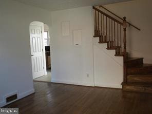 stairway featuring visible vents, arched walkways, and wood finished floors