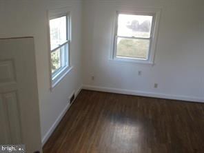 unfurnished room featuring baseboards and dark wood finished floors