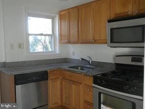 kitchen featuring appliances with stainless steel finishes, brown cabinets, and a sink