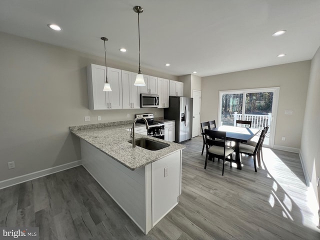 kitchen featuring kitchen peninsula, appliances with stainless steel finishes, sink, pendant lighting, and white cabinetry