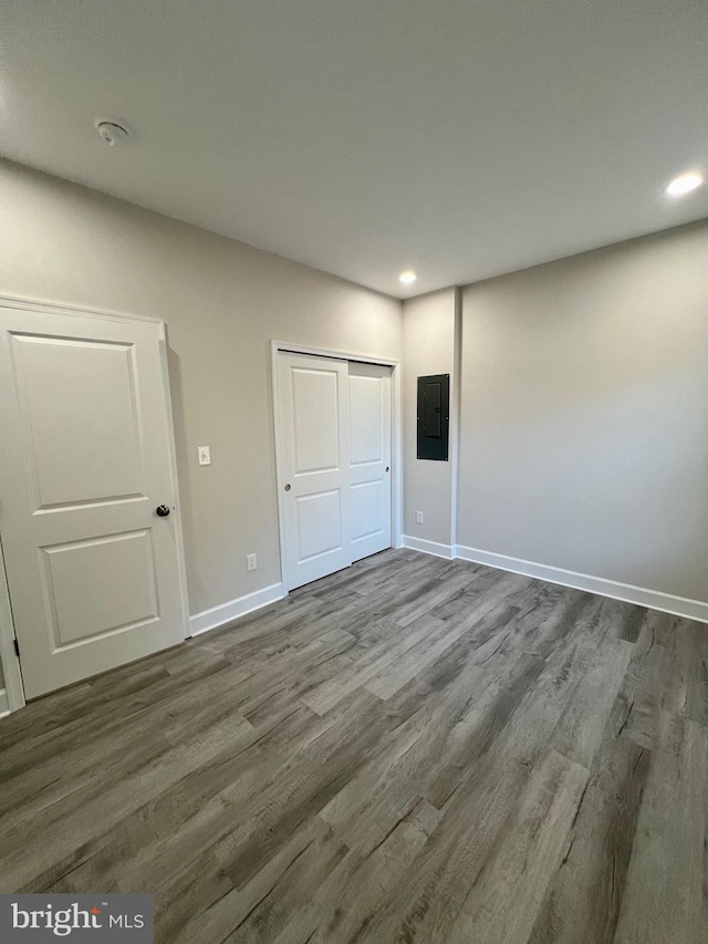 unfurnished bedroom featuring electric panel, a closet, and dark wood-type flooring