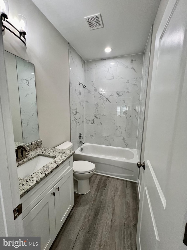 full bathroom with vanity, toilet, wood-type flooring, and tiled shower / bath