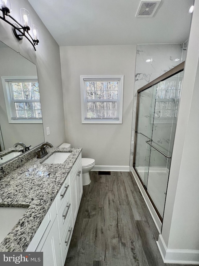 bathroom with wood-type flooring, vanity, a wealth of natural light, and a shower with door