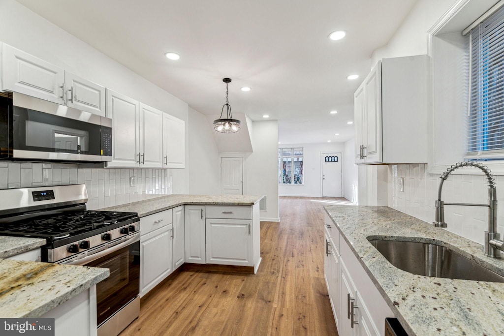 kitchen featuring light stone countertops, sink, hanging light fixtures, white cabinets, and appliances with stainless steel finishes