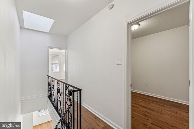 corridor with a skylight, dark hardwood / wood-style flooring, and a healthy amount of sunlight