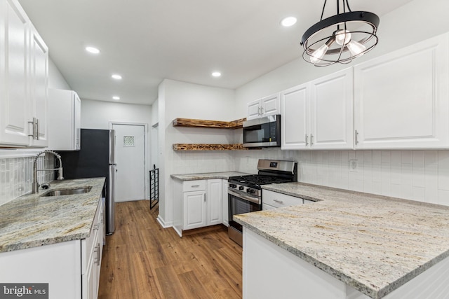 kitchen featuring white cabinets, decorative light fixtures, backsplash, and appliances with stainless steel finishes