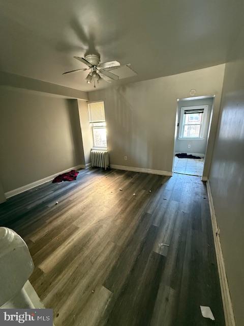 interior space with ceiling fan, dark hardwood / wood-style flooring, and radiator heating unit