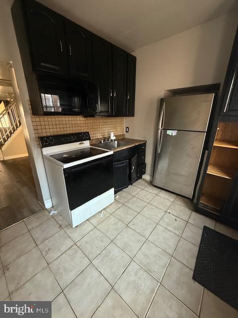 kitchen featuring sink, white range with electric stovetop, backsplash, stainless steel fridge, and light tile patterned floors