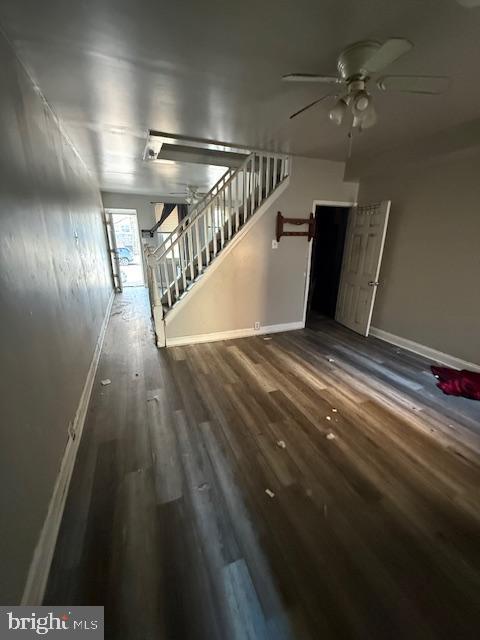 unfurnished living room with dark hardwood / wood-style flooring and ceiling fan