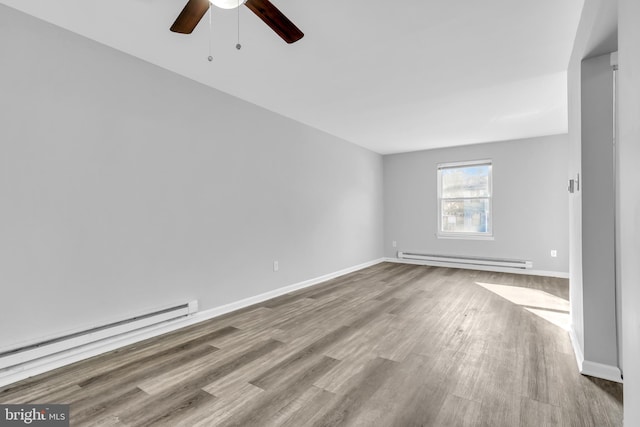 spare room with ceiling fan, light wood-type flooring, and a baseboard heating unit