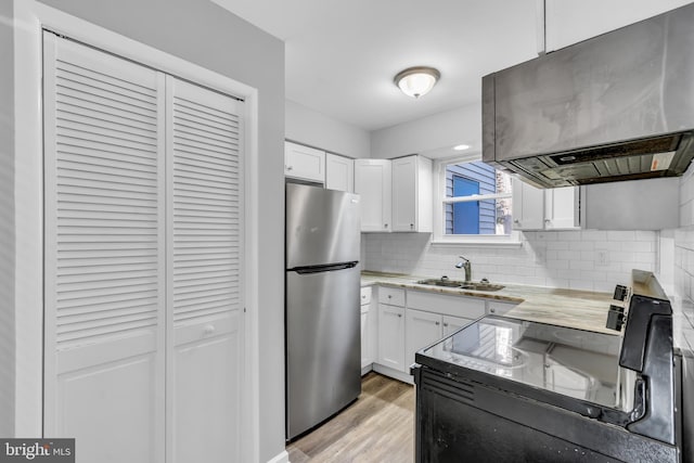 kitchen featuring decorative backsplash, stainless steel fridge, white cabinetry, and sink