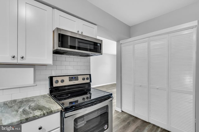 kitchen featuring decorative backsplash, light stone countertops, dark hardwood / wood-style flooring, stainless steel appliances, and white cabinets