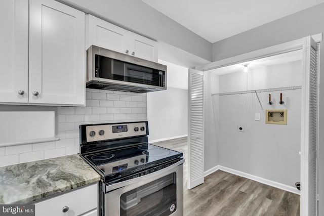 kitchen with tasteful backsplash, light stone counters, stainless steel appliances, white cabinets, and hardwood / wood-style floors