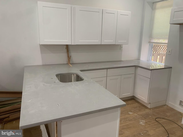 kitchen with kitchen peninsula, white cabinetry, and sink