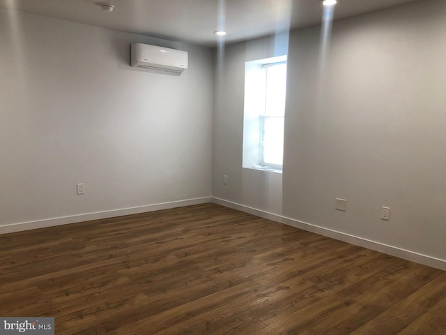 spare room with a wall unit AC and dark wood-type flooring